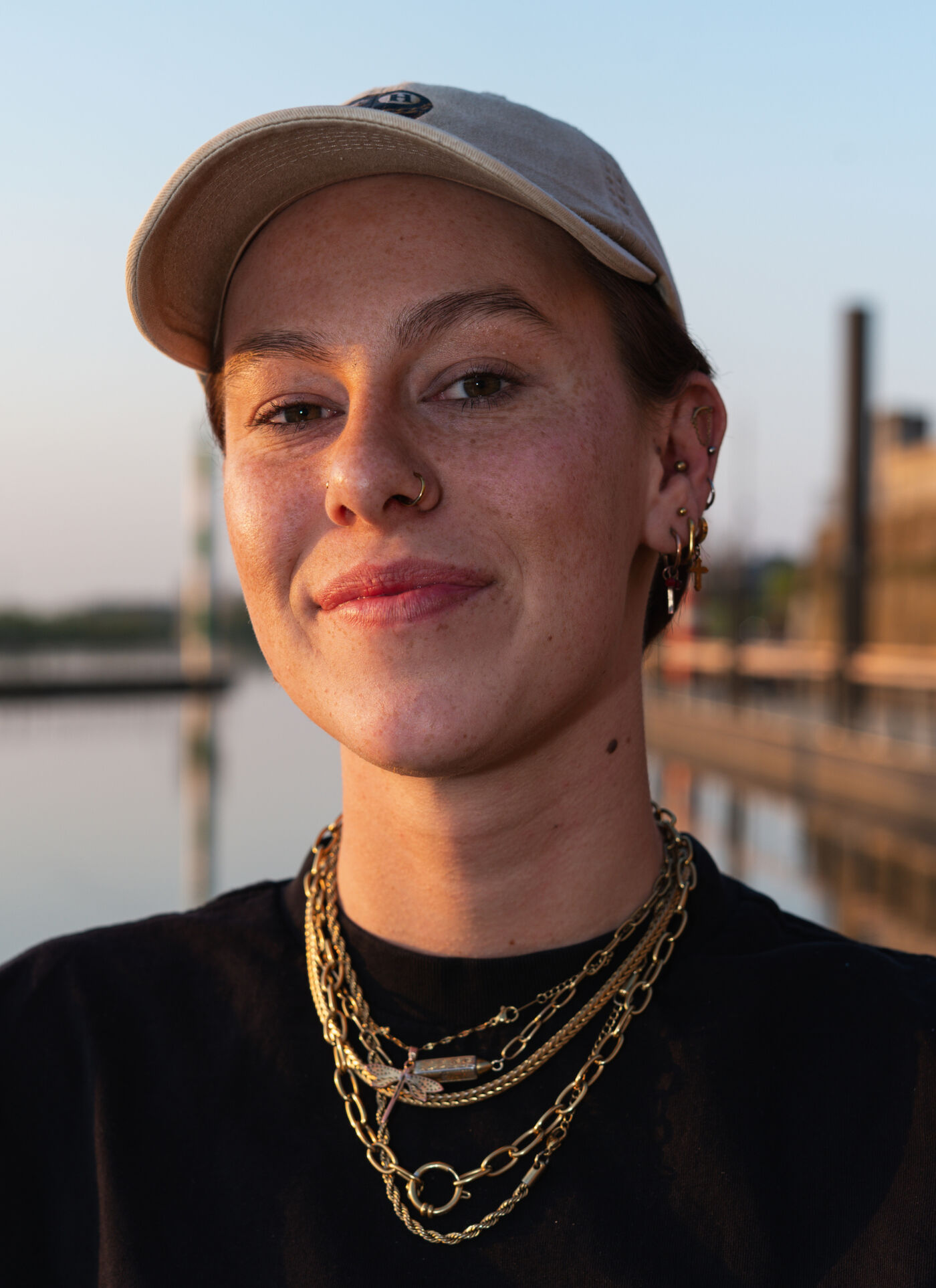 Hermke, vrijwilliger, met pet en gouden kettingen bij zonsondergang aan het water